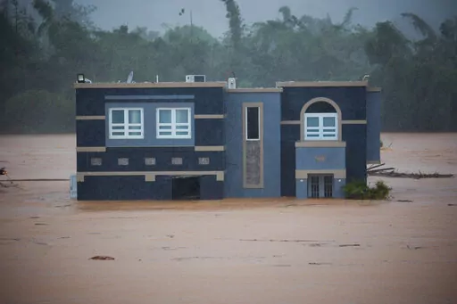 A home is submerged in floodwaters caused by Hurricane Fiona in Cayey, Puerto Rico, Sunday, Sept. 18, 2022.  According to authorities three people were inside the home and were reported to have been rescued.  (AP Photo/Stephanie Rojas)