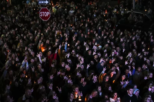 People sign "I love you" while gathered at a vigil for the victims of Wednesday's mass shootings, Oct. 29, 2023, outside the Basilica of Saints Peter and Paul in Lewiston, Maine. A commission investigating the shooting that killed 18 people is scheduled to hear from a police agency that had contact with the shooter before he committed the killings. Maine Gov. Janet Mills and Attorney General Aaron Frey assembled the commission to review the events that led up to the shootings at a bowling alley 