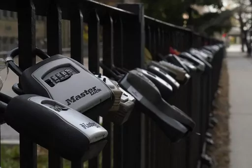 Key lock boxes for real estate showings hang on a fence outside a high-rise condominium building, Oct. 27, 2022, in Chicago. The cost of hiring a real estate agent to buy or sell a home is poised to change along with decades-old rules that have helped determine broker commissions. (AP Photo/Kiichiro Sato, File)
