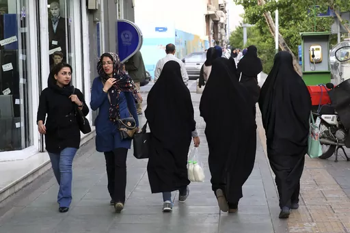 Iranian women make their way along a sidewalk in downtown Tehran, Iran, Tuesday, April 26, 2016. Iranian police have announced a new campaign to force women to wear the Islamic headscarf. Morality police returned to the streets on Sunday, 10 months after the death of a woman in their custody sparked nationwide protests. (AP Photo/Vahid Salemi, File)