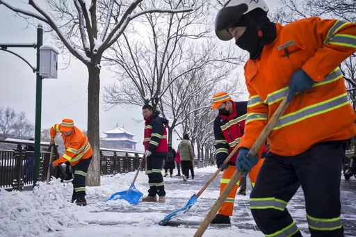 City workers clear the snow on a pathway near the Forbidden City after a snow fall in Beijing, Monday, Dec. 11, 2023. An overnight snowfall across much of northern China prompted road closures and the suspension of classes and train service on Monday.(AP Photo/Andy Wong)