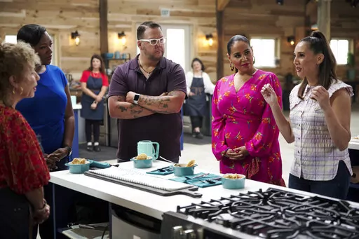 Judges Tiffany Derry, from second left, Graham Elliot, host Alejandra Ramos and judge Leah Cohen  gather around d a contestant’s station in a scene from the competition series "The Great American Recipe." (PBS via AP)