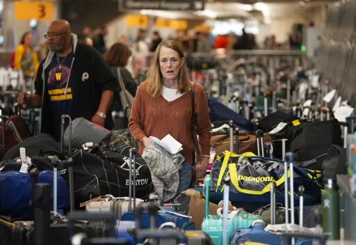 A traveler wades through the field of unclaimed bags at the Southwest Airlines luggage carousels at Denver International Airport, Tuesday, Dec. 27, 2022, in Denver. (AP Photo/David Zalubowski)