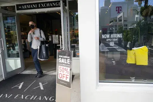 For sale and hiring signs are displayed at an Armani Exchange store, Friday, Jan. 21, 2022, in Miami Beach, Fla. (AP Photo/Marta Lavandier)