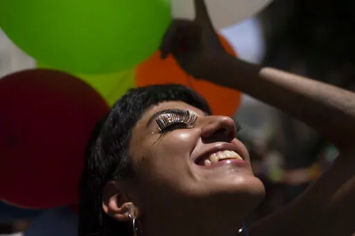 A reveler smiles during an unofficial carnival block party referred to as "blocos", in Rio de Janeiro, Brazil, Saturday, Feb. 26, 2022. City Hall banned all blocos, the tightly packed street parties attended by those who cannot or don't want to buy pricey tickets for the official parade at the Sambadrome, due to a wave of the Omicron variant. (AP Photo/Silvia Izquierdo)