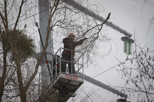 Workers of the electricity supply company DTEK maintain power lines by cutting off excess branches in Kyiv, Ukraine, Thursday, Dec. 8, 2022. Ukrainian utility crews struggling to patch up power lines during a two-month Russian military blitz targeting Ukrainian infrastructure are learning to adapt. And just as on the battlefield, Ukrainians are learning to respond quickly on the new energy front drawn inside homes, hospitals, offices, and schools in yet another act of defiance against a powerful
