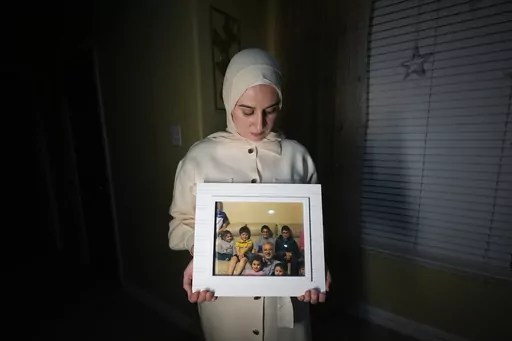 Maryam Kamalmaz hold a photo of her father with some of his 14 grandchildren in Grand Prairie, Texas, Jan. 17, 2024. By any standard, the past 18 months have been remarkable for getting wrongfully detained Americans home. But not so for Kamalmaz, who has had no trace of her father, Majd Kamalmaz, since the psychologist from Texas was stopped at a checkpoint in Syria in 2017 after traveling there to visit an elderly family member. He remains one of several Americans missing in Syria, including jo