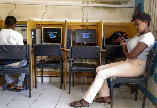 A customer uses the Wi-Fi on her mobile phone at an internet cafe in the low-income Kibera neighborhood of Nairobi, Kenya on Sept. 29, 2021. Facebook has failed to catch Islamic State group and al-Shabab extremist content in posts aimed at East Africa as the region remains under threat from violent attacks and Kenya prepares to vote in a closely contested national election, according to a new study released Wednesday, June 15, 2022. (AP Photo/Brian Inganga, File)
