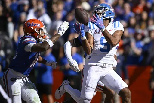 Mississippi wide receiver Tre Harris (9) catches a pass in front of Florida defensive backs Bryce Thornton, left, and Dijon Johnson (obscured at rear) for a 43-yard touchdown during the first half of an NCAA college football game, Saturday, Nov. 23, 2024, in Gainesville, Fla. (AP Photo/Phelan M. Ebenhack)