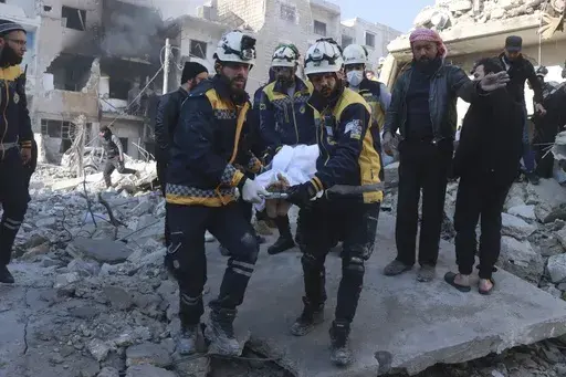 This photo provided by the Syrian Civil Defence White Helmets, which has been authenticated based on its contents and other AP reporting, shows Syrian White Helmets civil defence workers carry a victim after the Syrian government forces hit Idlib city, Syria, Monday, Dec. 2, 2024. (Syrian Civil Defence White Helmets via AP)