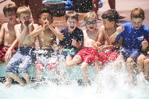 The photo released by the American Camp Association shows young boys splashing at the Tom Sawyer Camp pool in Pasadena, Calif., on July 11, 2019. After two pandemic summers, many families are venturing back into what they hope will be a more normal summer-camp experience. (Lisa Phelan/American Camp Association via AP)