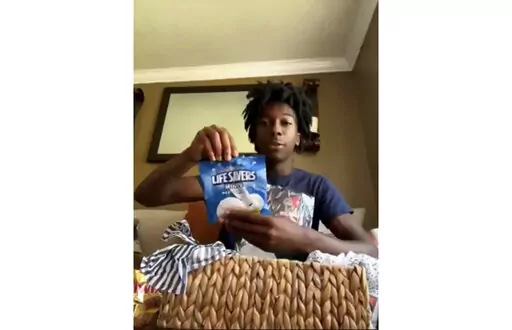 CORRECTS FIRST NAME TO CORION INSTEAD OF ORION - During a Zoom call, Friday, July 8, 2022, Corion Evans poses with candy gifted to him from the motorists he saved after their car drove off the Interstate 10 boat launch and into the Pascagoula River, in Mississippi, early Sunday, July 3. (AP Photo/Carrie Antlfinger)