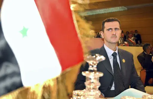 Syrian President Bashar Assad looks on at his country's flag at the opening of the 16th ordinary session of Arab Summit in Tunis, May 22, 2004. (AP Photo/Amr Nabil, File)