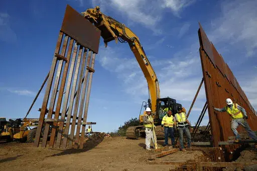 Construction crews install new border wall sections seen from Tijuana, Mexico., Jan. 9, 2019. An anti-immigration group scored a legal victory on Friday, Aug. 12, 2022, in its federal lawsuit arguing the Biden administration violated environmental law when it halted construction of the U.S. southern border wall and sought to undo other immigration policies by former President Donald Trump. (AP Photo/Gregory Bull, File)