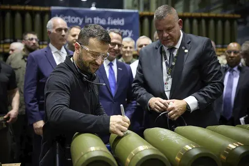 In this image provided by the Office of the Ukrainian Presidency, Ukrainian President Volodymyr Zelenskyy, left, is watched by Rich Hansen, the commander's representative for the Scranton Army Ammunition Plant, while signing military ordnance in Scranton, Pa., Sunday, Sept. 22, 2024. (Office of the Ukrainian Presidency via AP, File)