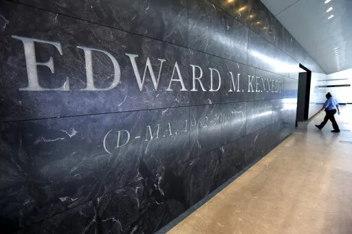 A passer-by walks near the engraved name of the late U.S. Sen. Edward M. Kennedy near the main entrance to the Edward M. Kennedy Institute, in Boston, March 23, 2015. An Associated Press review finds state and local governments have spent nearly $1 billion worth of federal coronavirus aid on projects that have little to do with combating the pandemic. Lawmakers delivered $5 million to pay off debts of the Edward M. Kennedy Institute for the U.S. Senate, a nonprofit established to honor the senat