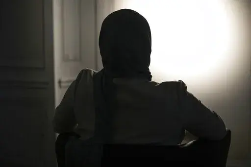 The sister, who refused to show and identify, of a woman imprisoned in Turkey is silhouetted during an interview with The Associated Press in Paris, Wednesday, Feb. 16, 2022. Shatz and a team of European lawyers filed a case against Greece at the European Court of Human Rights on behalf of a 32-year-old French woman who accuses the Hellenic country of forcibly pushing her back across the border from Greece to Turkey, where she claims she is a victim of political persecution. The woman, who is al