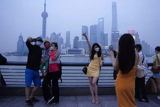 Residents pose for photos along the bund, Wednesday, June 1, 2022, in Shanghai. Traffic, pedestrians and joggers reappeared on the streets of Shanghai on Wednesday as China's largest city began returning to normalcy amid the easing of a strict two-month COVID-19 lockdown that has drawn unusual protests over its heavy-handed implementation. (AP Photo/Ng Han Guan)