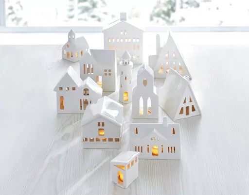 This image provided by Crate & Barrel shows their collection of white ceramic buildings. Crate & Barrel's collection includes alpine homes and hotels as well as midcentury split levels and ranch homes. Add a tealight for a welcoming glow. (Crate & Barrel via AP)