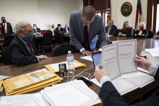 Shawn Still, now a Georgia Republican state senator, leans over to sign electoral certificates voting for Donald Trump and Vice President Mike Pence at the Georgia Capitol, Dec. 14, 2020, in Atlanta, during a meeting of Republican electors. The meeting of the electors has become a key element in the prosecution of Trump and 18 others in Georgia. Smith is one of the four people present that day who was indicted by a Fulton County grand jury in August 2023 on charges that he conspired to illegally