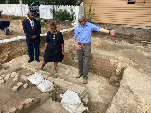 From left, Reginald F. Davis, pastor of First Baptist Church, Connie Matthews Harshaw, a member of First Baptist, and Jack Gary, Colonial Williamsburg's director of archaeology, stand at the brick-and-mortar foundation of one the oldest Black churches in the U.S. on Oct. 6, 2021, in Williamsburg, Va. Experts announced Thursday, April 6, 2023, that three men whose graves were found at the site were members of the church in the early 19th Century. (AP Photo/Ben Finley, File)