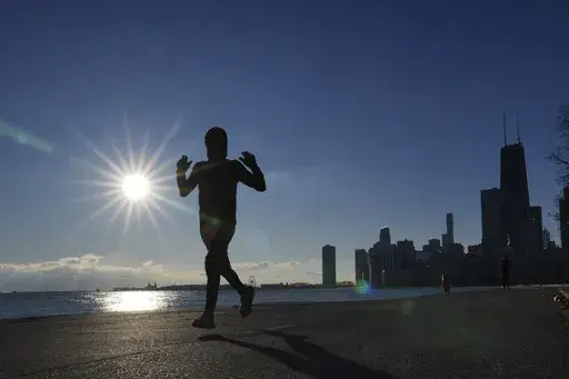 A lone jogger traverses the Lake Michigan shoreline on a bike and running path in below freezing temperatures Friday, Jan. 3, 2025, in Chicago. (AP Photo/Charles Rex Arbogast)