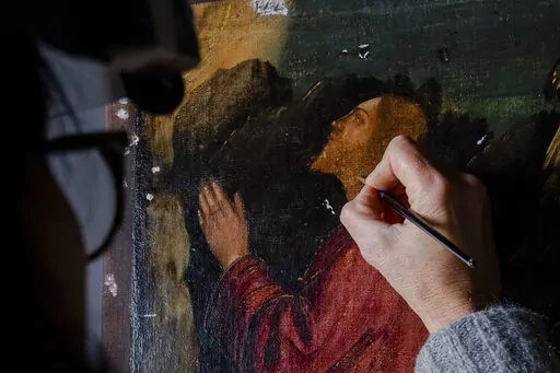 Restorer Valentina Piovan works on Vittore Carpaccio's 1502 painting 'The agony in the garden' at the Dalmatian School in Venice, northern Italy, Wednesday, Dec. 7, 2022. On November 20th, the National Gallery of Washington inaugurated the first retrospective exhibition of Carpaccio’s works outside of Italy. It will run until February 12, 2023. (AP Photo/Domenico Stinellis)