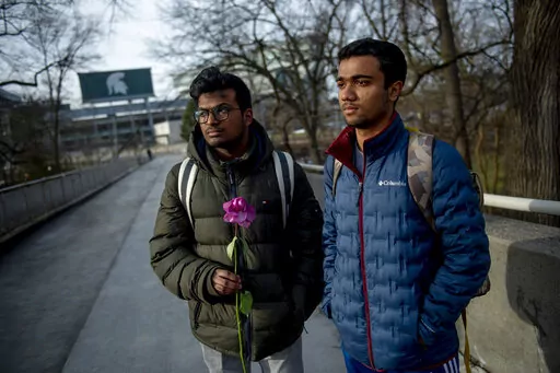 Michigan State international students Dheeraj Thota, left, and Chirag Bhansari, both freshman studying computer science, found a single rose on their walk to class as campus opens back up for the first day of classes on Monday, Feb. 20, 2023 at Michigan State University in East Lansing, Mich. Michigan State University is set to return to classes Monday, with officials saying they hope a return to familiarity may help the community heal. (Jake May/The Flint Journal via AP)