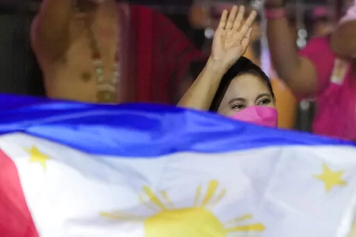 Presidential candidate, current Vice President Leni Robredo greets supporters as a Philippine flag is waved during a campaign rally that coincides with her birthday in Pasay City, Philippines on Sunday, April 24, 2022. Followers from diverse backgrounds, families with their grandparents and children, activists, doctors, Catholic church people, TV and movie stars, farmers, students, have jammed Robredo's fiesta-like campaign rallies in the tens of thousands in recent weeks. She called the emergin