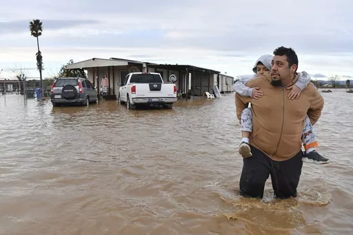 Ryan Orosco, of Brentwood, carries his son Johnny, 7, on his back while his wife Amanda Orosco waits at the front porch to be rescued from their flooded home on Bixler Road in Brentwood, Calif., Jan. 16, 2023. The National Oceanic and Atmospheric Administration announced Monday, Sept. 11, that there have been 23 weather extreme events in America that cost at least $1 billion this year through August, eclipsing the year-long record total of 22 set in 2020. (Jose Carlos Fajardo/Bay Area News Group