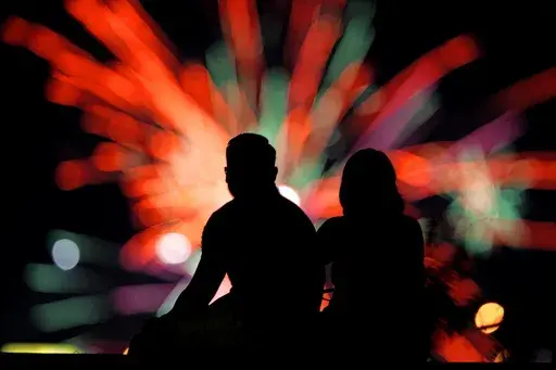 People watch distant fireworks from a park on July 4, 2022, in Kansas City, Mo. Warehouse membership club Costco said it would be closed on July 4th, 2024, but the vast majority of major national retailers will be open, with some offering promotional sales to lure customers. (AP Photo/Charlie Riedel, File)