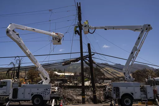 Electric crews work on power lines in the aftermath of a devastating wildfire in Lahaina, Hawaii, Thursday, Aug. 17, 2023. Lawyers for Lahaina residents and business owners told a court Tuesday, Sept. 5, that cable TV and telephone companies share in responsibility for the wildfires that devastated the island. (AP Photo/Jae C. Hong, File)