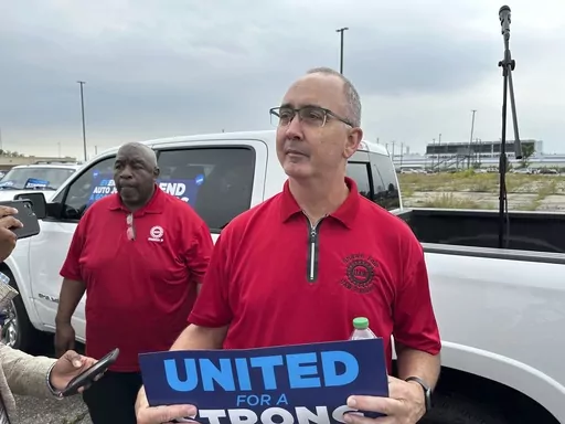 United Auto Workers President Shawn Fain holds up a sign at a union rally held near a Stellantis factory Wednesday, Aug. 23, 2023, in Detroit. The demands that a more combative United Auto Workers union has made of General Motors, Stellantis and Ford — demands that even the UAW's president has called “audacious” — are edging it closer to a strike when its current contract ends Sept. 14. (AP Photo/Mike Householder, File)