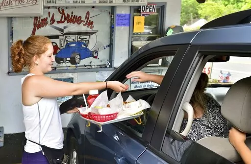  In this Tuesday June 23, 2015 photo, Jim's Drive-In waitress Aly King delivers an order to a waiting customer at the iconic restaurant in Lewisburg, W.Va. A program offering $20,000 in cash and incentives for remote workers to move to West Virginia as part of a population push has chosen 33 people for its second class of newcomers to live in the Greenbrier Valley, which includes Lewisburg. (Bob Wojcieszak/Daily Mail via AP, File)