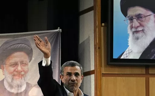 Iran's hard-line former President Mahmoud Ahmadinejad waves to the media as he leaves at the conclusion of a press briefing beside portraits of the Supreme Leader Ayatollah Ali Khamenei, top right, and the late President Ebrahim Raisi after registering his name as a candidate for the June 28 presidential election at the Interior Ministry, in Tehran, Iran, Sunday, June 2, 2024. Ahmadinejad registered Sunday as a possible candidate for the presidential election, seeking to regain the country's top