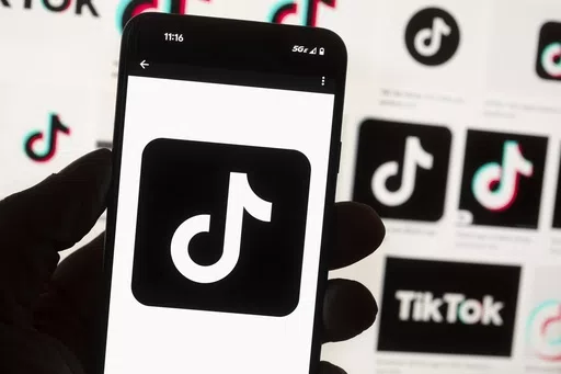 The TikTok logo is displayed on a mobile phone in front of a computer screen, Oct. 14, 2022, in Boston. TikTok is gearing up for a legal fight against a U.S. law that would force the social media platform to break ties with its China-based parent company or face a ban. A battle in the courts will almost certainly be backed by Chinese authorities as the bitter U.S.-China rivalry threatens the future of a wildly popular way for young Americans to connect online. (AP Photo/Michael Dwyer, File)