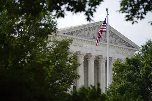 An American flag waves in front of the U.S. Supreme Court building in Washington, June 27, 2022. Supreme Court arguments are continuing long after a red light tells lawyers to stop. Arguments that usually lasted an hour have stretched beyond two this term so on many days it is well past lunchtime before the court breaks. (AP Photo/Patrick Semansky, File)