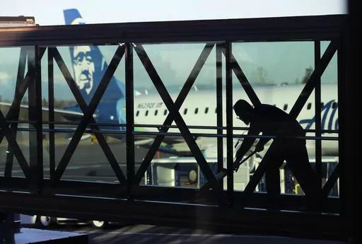 A worker cleans a jet bridge at Paine Field in Everett, Wash., before passengers board an Alaska Airlines flight on March 4, 2019. Seattle-based Alaska Airlines owns Horizon Air. An off-duty pilot riding in the extra seat in the cockpit of a Horizon Air passenger jet on Sunday, Oct. 22, 2023, tried to shut down the engines in mid-flight and had to be subdued by the crew, according to a pilot flying the plane. (AP Photo/Ted S. Warren, File)