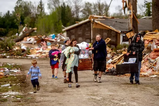 Resident Stephanie Kerwin, center, holds her baby Octavius in one arm and dog Pixie in the other as she and her family carry what they could salvage from her home in Nottingham Forest Mobile Home Park, Saturday, May 21, 2022, in Gaylord, Mich., following a tornado the day before. "This morning is when it first hit me...I could have lost people that I really love. I am so grateful," Kerwin said. (Jake May/MLive.com/The Flint Journal via AP)
