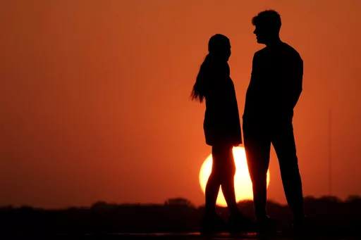 People are silhouetted against the sky as the sun sets Wednesday, May 11, 2022, in Kansas City, Mo. According to a report released by the U.S. Centers for Disease Control and Prevention on Thursday, April 27, 2023, the first years of the pandemic saw a huge decline in high school students having sex. Teen sex was already becoming less and less common before COVID-19. (AP Photo/Charlie Riedel, File)