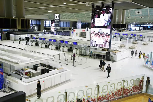 Passengers walk through the ticketing counter floor for international flights at the Narita International Airport in Narita, east of Tokyo, on Dec. 2, 2021. Hundreds of thousands of foreigners have been denied entry to study, work or visit families in Japan, which has kept its doors closed to most overseas visitors during the pandemic. (AP Photo/Hiro Komae, File)