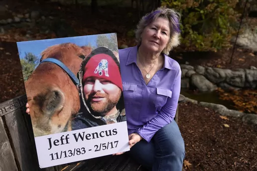 Lynn Wencus, of Wrentham, Mass., holds a photograph of her son Jeff while seated in a garden at her home, in Wrentham, Tuesday, Nov. 7, 2023. Wencus lost Jeff to a heroin overdose in 2017. Families who lost loved ones to overdose are divided over OxyContin maker Purdue Pharma's plan to settle lawsuits over the toll of opioids with governments. It could provide billions to address an overdose epidemic and pay some victims. But it would also protect members of the Sackler family who own the compan
