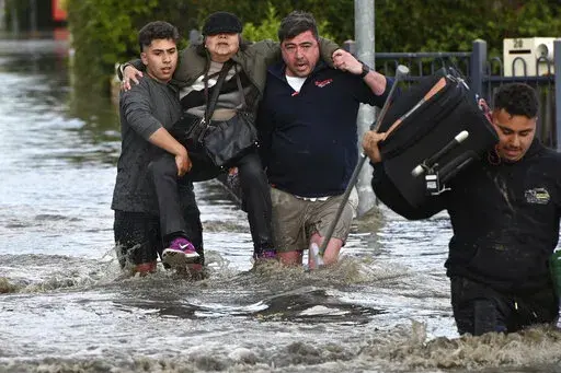 A woman is rescued from floodwater in Melbourne, Australia's suburb of Maribyrnong, Friday, Oct. 14, 2022. Rivers across Australia's most populous states, New South Wales and Victoria, and the island state of Tasmania were rising dangerously with catchments soaked by months of above-average rainfall. (Erik Anderson/AAP Image via AP)
