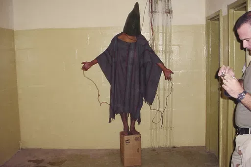 This late 2003 photo obtained by The Associated Press shows an unidentified detainee standing on a box with a bag on his head and wires attached to him in the Abu Ghraib prison in Baghdad, Iraq. A trial scheduled to begin Monday, April 15, 2024, in U.S. District Court in Alexandria, Va., will be the first time that survivors of Iraq’s Abu Ghraib prison will bring their claims of torture to a U.S. jury. Twenty years ago, photos of abused prisoners and smiling U.S. soldiers guarding them shocked
