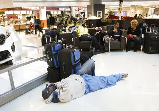 A man sleeps on the terminal floor at Hartfield-Jackson Atlanta International Airport on Dec. 18, 2017, in Atlanta. Transportation Secretary Pete Buttigieg has warned airlines that his department could draft new rules around passenger rights if the carriers don’t give more help to travelers trapped by flight cancellations and delays. The Transportation Department on Friday, Aug. 19, 2022, released a copy of the letters, which it said were sent to CEOs of the major U.S. airlines, their regional