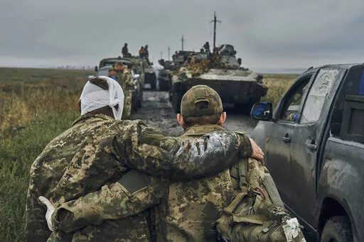 A Ukrainian soldier helps a wounded comrade on the road in reclaimed territory in the Kharkiv region, Ukraine, on Sept. 12, 2022. Some experts say the yearlong conflict that already has killed tens of thousands and reduced whole cities to smoldering ruins could drag on for many more years. (AP Photo/Kostiantyn Liberov, File)