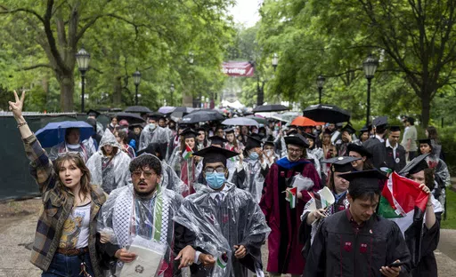 University of Chicago students, including Youssef Hasweh, second from left, one of four students the university is withholding degrees from due to their involvement in an encampment, walk out of the university's convocation ceremony in support of Palestinians on Saturday, June 1, 2024, in Chicago. (Vincent Alban/Chicago Tribune via AP)