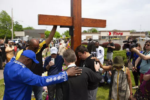 A group prays at the site of a memorial for the victims of the Buffalo supermarket shooting outside the Tops Friendly Market on Saturday, May 21, 2022, in Buffalo, N.Y.   Tops was encouraging people to join its stores in a moment of silence to honor the shooting victims Saturday at 2:30 p.m., the approximate time of the attack a week earlier. Buffalo Mayor Byron Brown also called for 123 seconds of silence from 2:28 p.m. to 2:31 p.m., followed by the ringing of church bells 13 times throughout t