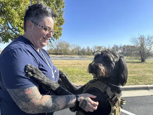 Air Force Staff Sgt. Heather O'Brien holds her labradoodle service dog, Albus, on Thursday, Nov. 7, 2024, in Kansas City, Kan. O'Brien is a part of Dogs 4 Valor that helps retired veterans and first responders in the Kansas City area work with their service dogs to help manage depression, anxiety and other challenges. (AP Photo/Nick Ingram)
