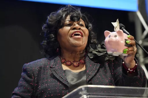 Addie Lee Green, Democratic nominee for Mississippi State Treasurer, holds a piggy bank with a $100 dollar bill stuffed in it, as she addresses the group of business leaders at the 2023 Hobnob, sponsored by the Mississippi Economic Council, in Jackson, Miss., Thursday, Oct. 26, 2023. (AP Photo/Rogelio V. Solis)